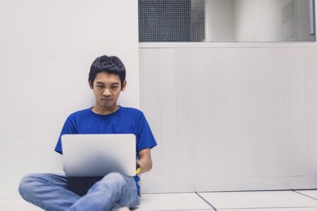 Asian man is working from home during Coronavirus or Covid-19. Work at home and using laptop. Work from home, Stay home. Social distancing.の写真素材