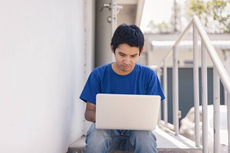Asian man is working from home during Coronavirus or Covid-19. Work at home and using laptop. Work from home, Stay home. Social distancing.の写真素材