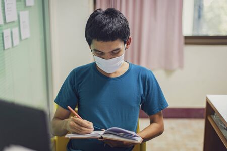 Coronavirus or covid-19. Asian men wearing mask protection, work from home with disinfectant gel.の写真素材