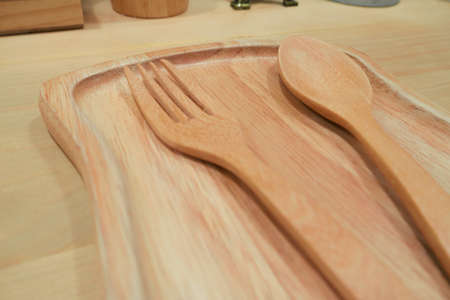 Wooden spoon and fork placed in wooden plates in restaurant at dinnerの写真素材