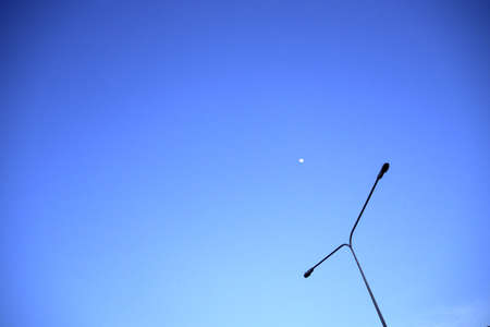 Power pole on the horizon in the evening time and moonの写真素材