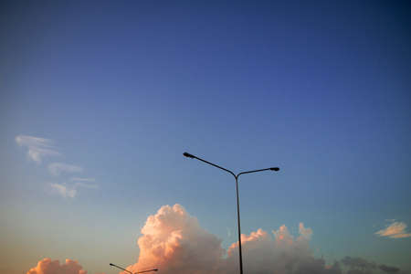 Electricity pylons on the sky with clouds in the evening time at sunsetの写真素材