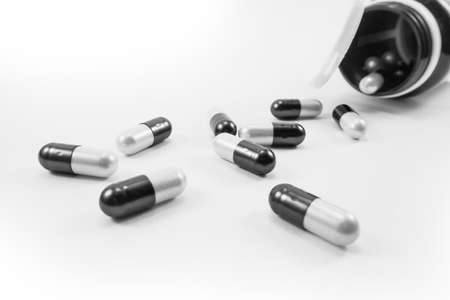 Capsules spilled out of a bottle on a white backgroundの写真素材