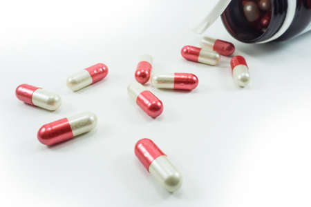 Capsules spilled out of a bottle on a white backgroundの写真素材
