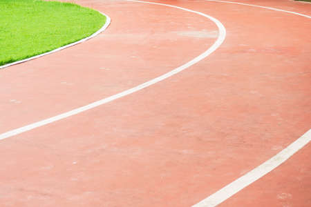 Running track and green field in sport park in evening time
