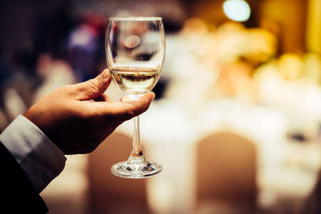 Men holding a glass of wine at a party at night.の写真素材