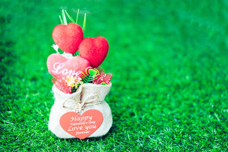 Heart-shaped Valentine's Day gifts in a sack on the grass in soft light.の写真素材