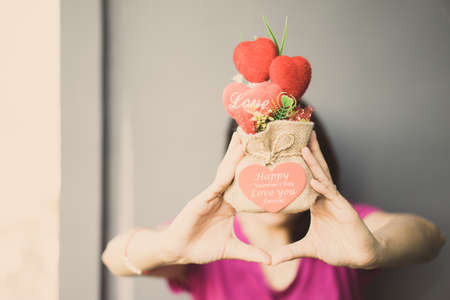 Heart-shaped gift in sack Lay hands on a woman on the wall.の写真素材
