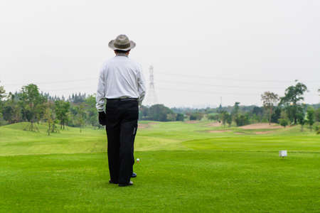 Old man golfing alone on a green golf course in sunshine.の写真素材