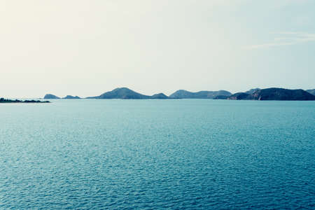 Peaceful blue sea and mountains in evening.の写真素材