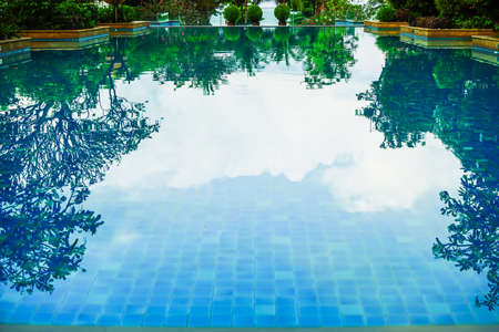 The pool is surrounded by trees at morning light.の写真素材
