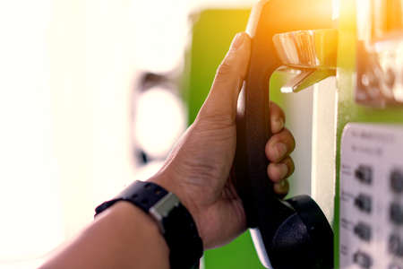 Hands that are holding a public phone to call emergency.