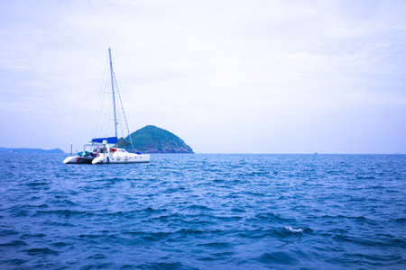 An island in the middle of the sea and a ship moored in the sea.の写真素材