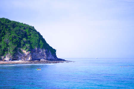 Island in the middle of the sea and boats rowing in the sea.の写真素材