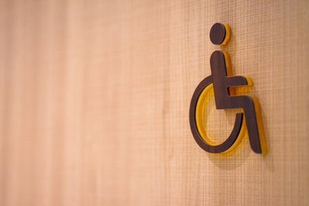 Wooden sign in front of a toilet for the disabled on a wooden background.の写真素材
