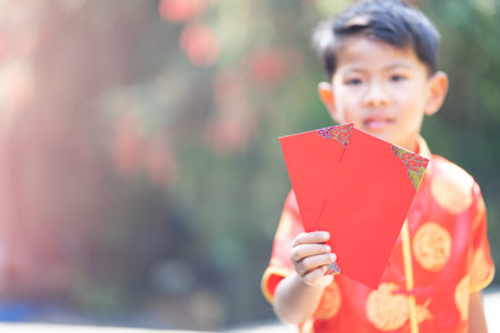 boy wearing red cheongsam holding chinese new year red envelope.の写真素材