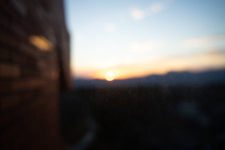 As the evening sun sets, the sky glows golden yellow through thick dusty glass.
