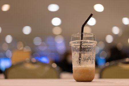 A plastic coffee cup that was almost empty was placed on the table. bokeh light background.