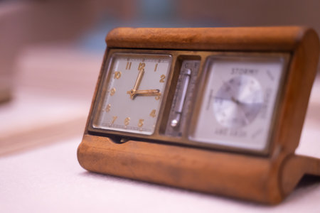 Wooden clock placed on white table, light blurred background.の写真素材