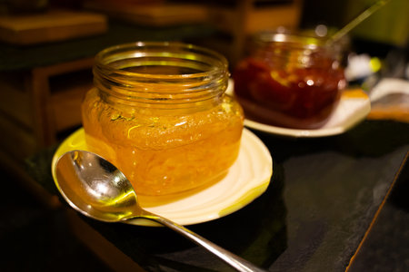 Delicious marmalade in glass jars on dark gray table.