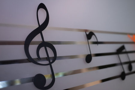 Black music notes on a white wall with shadows in the shade, no light.の写真素材