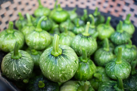 Little green pumpkins piled up in large numbers in a basket.
