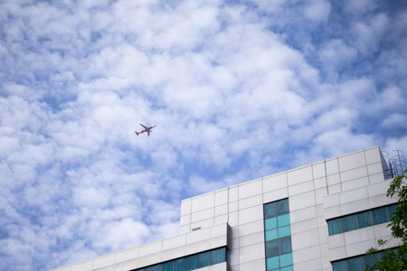 The clear sky saw the plane above the building.の写真素材