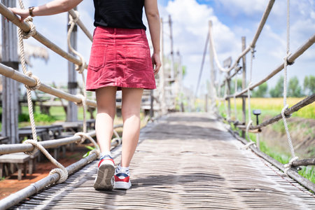 A woman walks on an old wooden bridge on a clear day.の写真素材