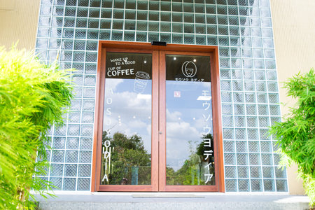 Ayutthaya, Thailand - September 20, 2023: Glass door entrance to a Japanese style coffee shop and bakery and text Wake up with a good cup of coffee.のeditorial素材