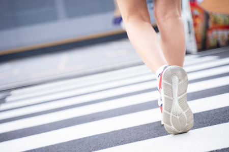 A woman walks on a road with a zebra crossing.