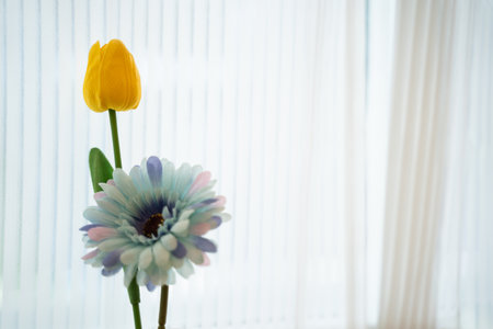 bright colored artificial flowers On the background white curtains.の写真素材