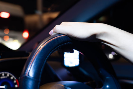 Male hands holding the steering wheel while driving a car at night.の写真素材