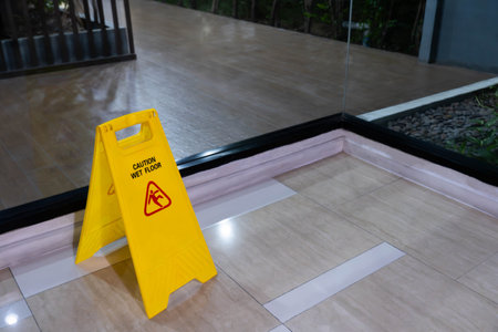 Yellow signs on the floor mark the area being cleaned. The floor is wet, be careful it's slippery.の写真素材