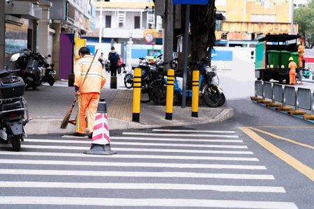Man sweeps the streets with a broom, clean city streets Clean the city from garbage. Municipal workers in orange uniforms sweep the streets.の写真素材