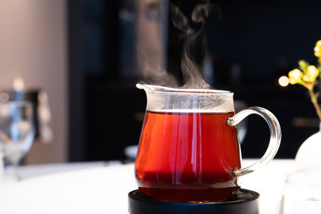 Hot tea in a glass with steam on the dining table.の写真素材