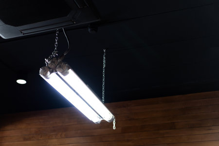 Long fluorescent tube ,LED bulbs and strips installed on the ceiling of a modern cafe.の写真素材