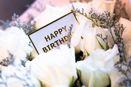 Close-up of happy birthday card on beautiful rose bouquet, bokeh light background.の写真素材