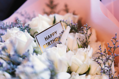 Close-up of happy birthday card on beautiful rose bouquet, bokeh light background.
