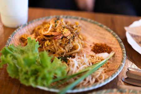 Pad Thai with fresh shrimp on a plate ready to eat on a wooden table in a restaurant.の写真素材