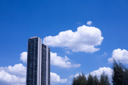 Blue sky with white clouds floating above city skyscrapers on a clear summer day.の写真素材