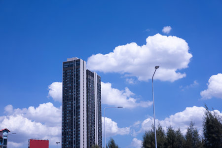 Blue sky with white clouds floating above city skyscrapers on a clear summer day.の写真素材