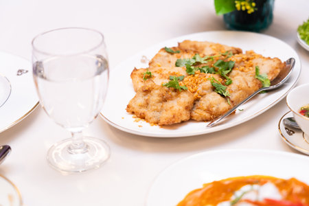 Fried pork with garlic and coriander garnish on a plate. Thai food on the dining table at lunchtime.の写真素材