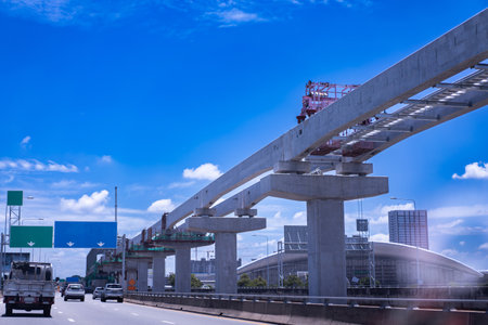 Construction site of transportation system, high-speed train overhead on pylons and tracks, efficient transportation development project, sky background.の写真素材
