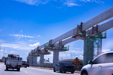 Construction site of transportation system, high-speed train overhead on pylons and tracks, efficient transportation development project, sky background.の写真素材