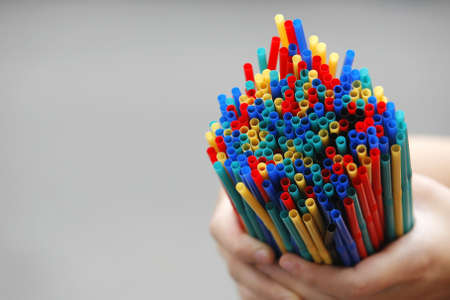 Hand holding many colored strawsの写真素材