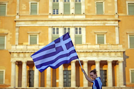 Athens, Greece - June 30, 2011: A Greek woman holds a flag in front of the Greek parliament during a protest in Athens, Greece.のeditorial素材