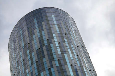 A tall round office building against a cloudy sky