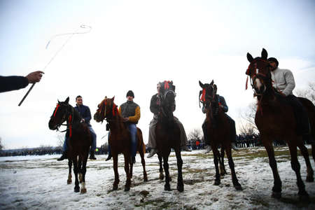 Pietrosani, Romania - January 7, 2013: Men prepare to ride their horses on a snowy field during a race organized in the village of Pietrosani, Romania to celebrate Epiphany. のeditorial素材