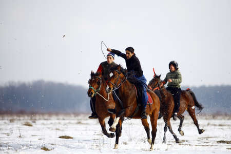 Pietrosani, Romania - January 7, 2013: Men ride their horses on a snowy field during a race...