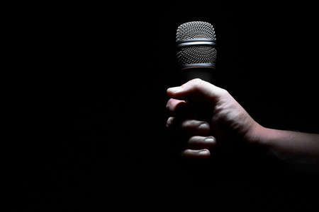 Studio shot of a hand holding a microphone, on blackの写真素材